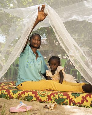 Moeder en dochter in Burkina Faso zitten onder een muskietennet