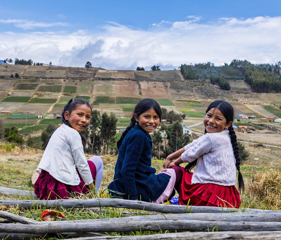 Belen, Nayeli en Maria uit Bolivia zitten samen op een grashelling.